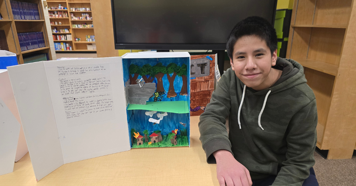 student smiling next to literacy project